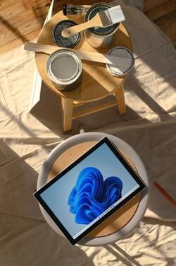 A côté de pots de peintures ouverts, une tablette informatique avec l'image d'une vague